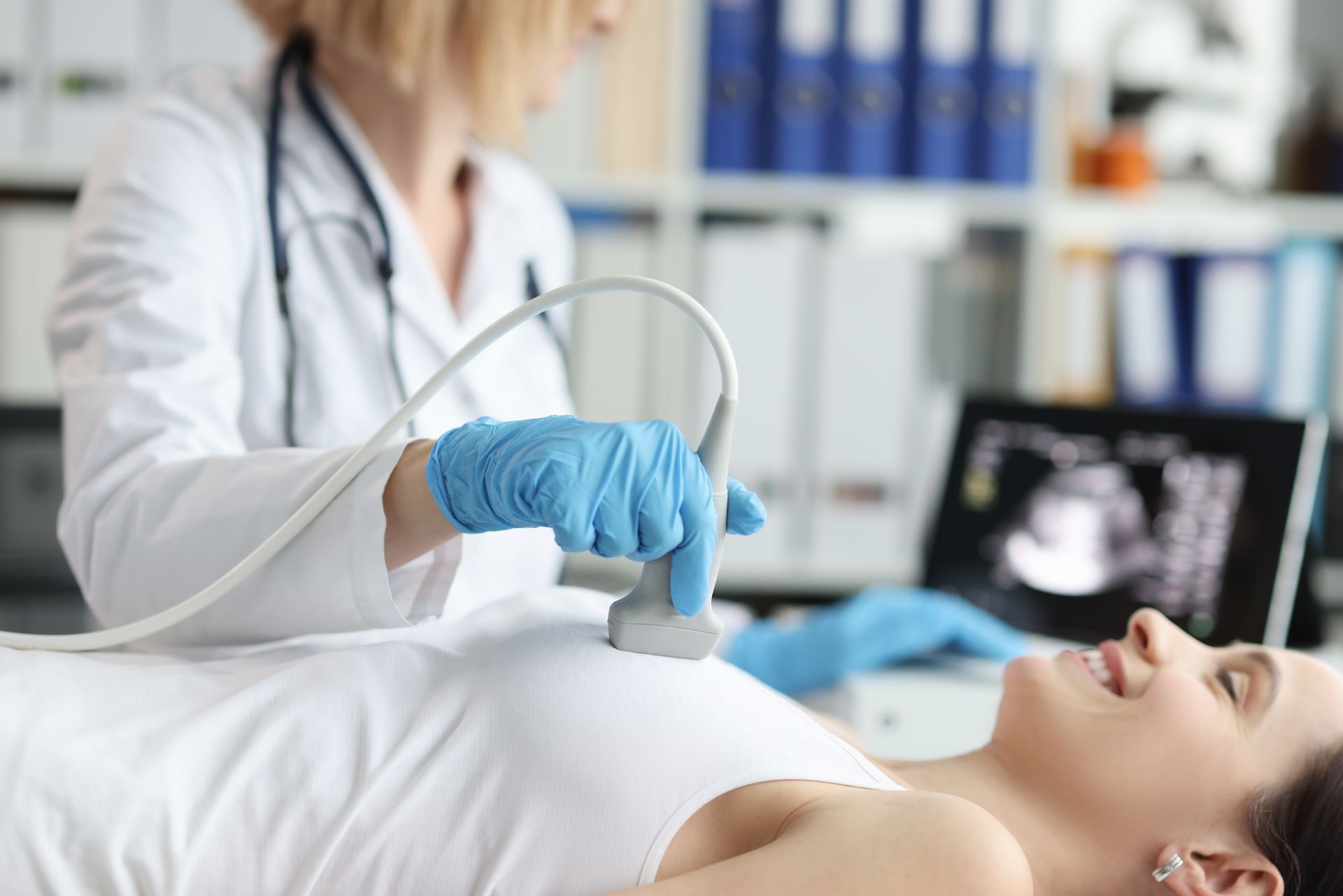 A pregnant woman is getting an ultrasound from a doctor.