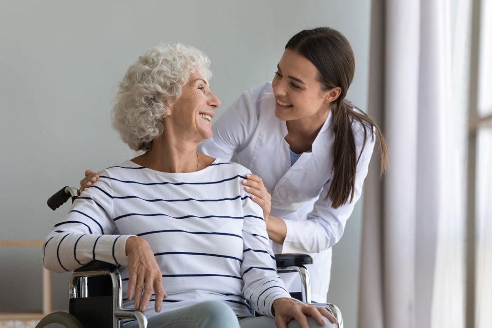 A Person in a Wheelchair Smiling with a Nurse — Adaptive Care Pty Ltd In Tarneit, VIC