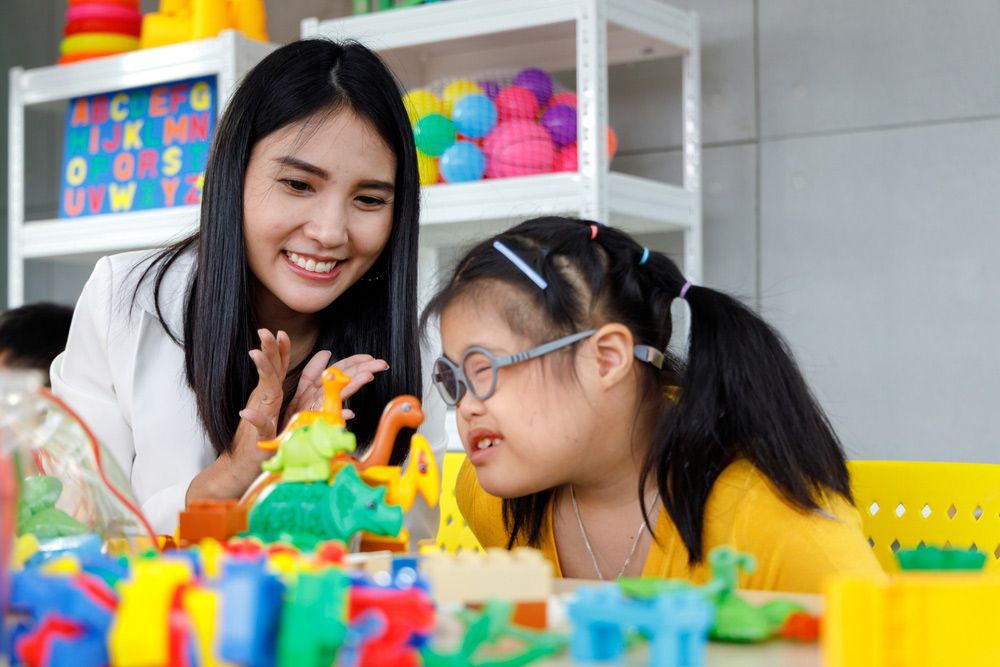A Woman is Playing With a Little Girl Who is Wearing Glasses — Adaptive Care Pty Ltd In Tarneit, VIC