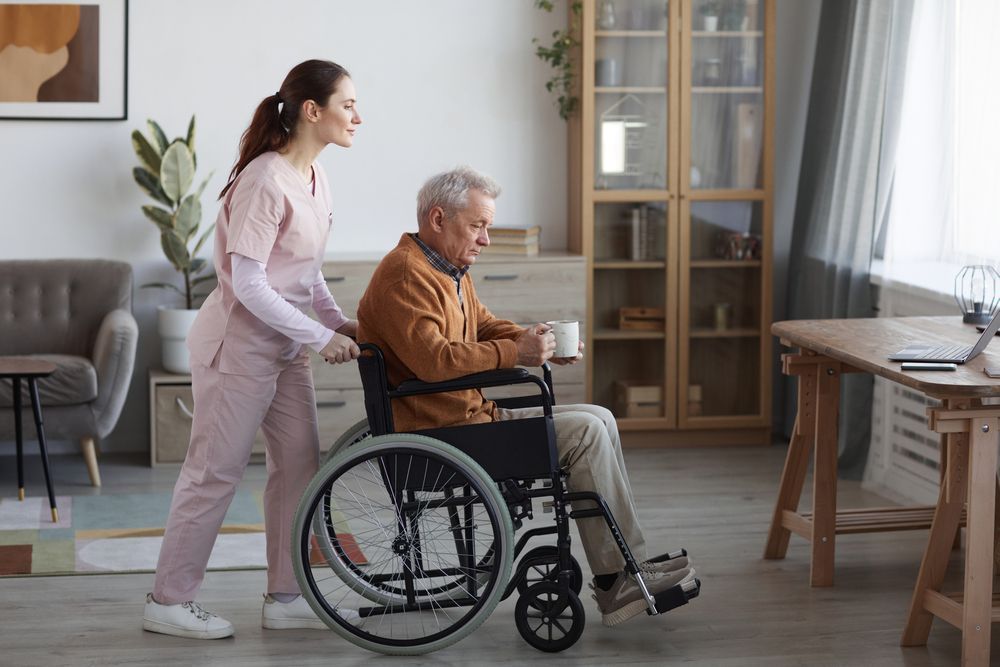 Senior Man in Wheelchair With Nurse Assisting Him at Retirement Home — Adaptive Care Pty Ltd In Tarneit, VIC