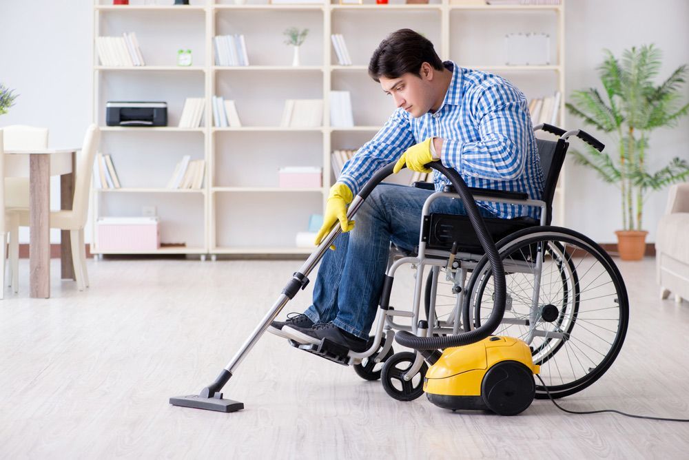 Disabled Man Cleaning Home with Vacuum Cleaner — Adaptive Care Pty Ltd In Tarneit, VIC