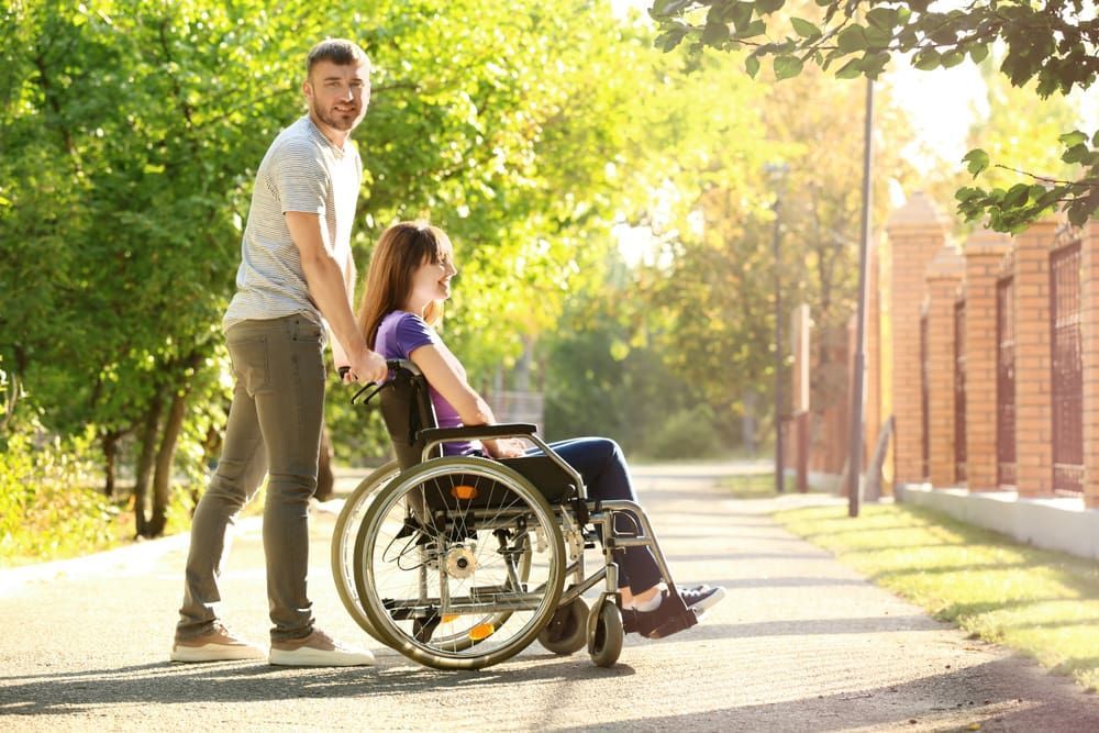 A Man Pushing A Girl On A Wheelchair — Adaptive Care Pty Ltd In Tarneit, VIC