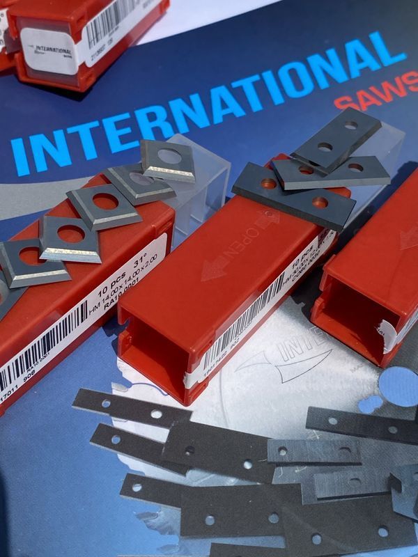 Lame e componenti per seghe in metallo rosso e grigio esposti sulla confezione di International Saw.