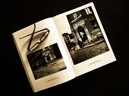 Een open boek met zwart-witfoto's van een gebouw en een bril.
