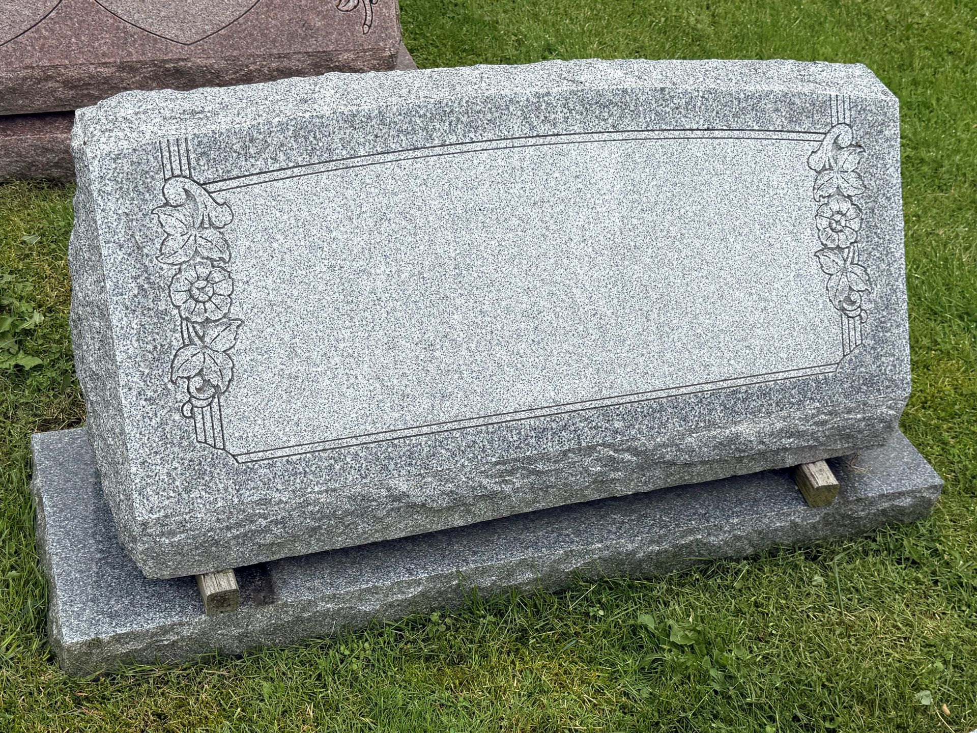 A gravestone is sitting in the grass in a cemetery.