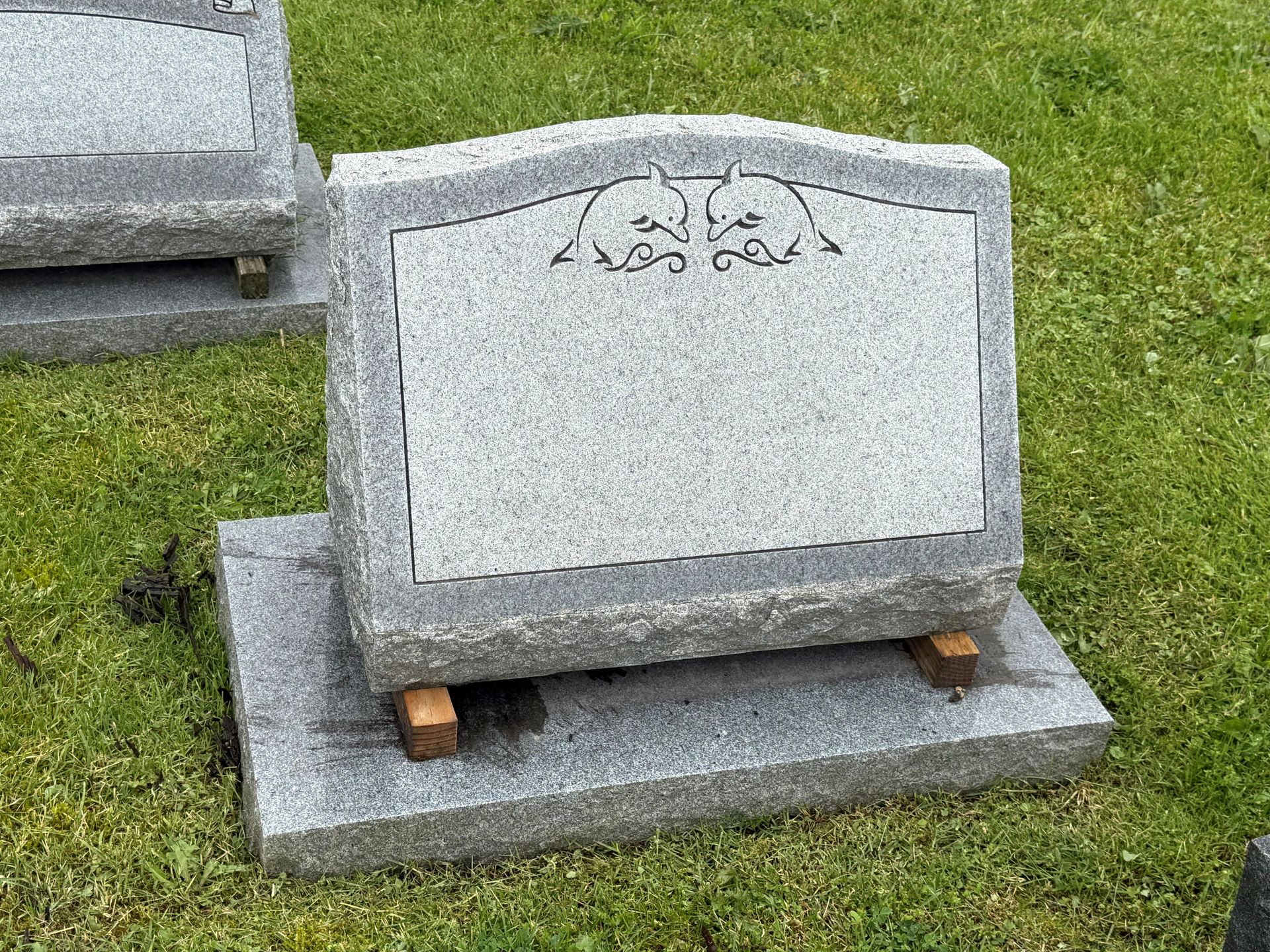 A gravestone is sitting in the grass in a cemetery.