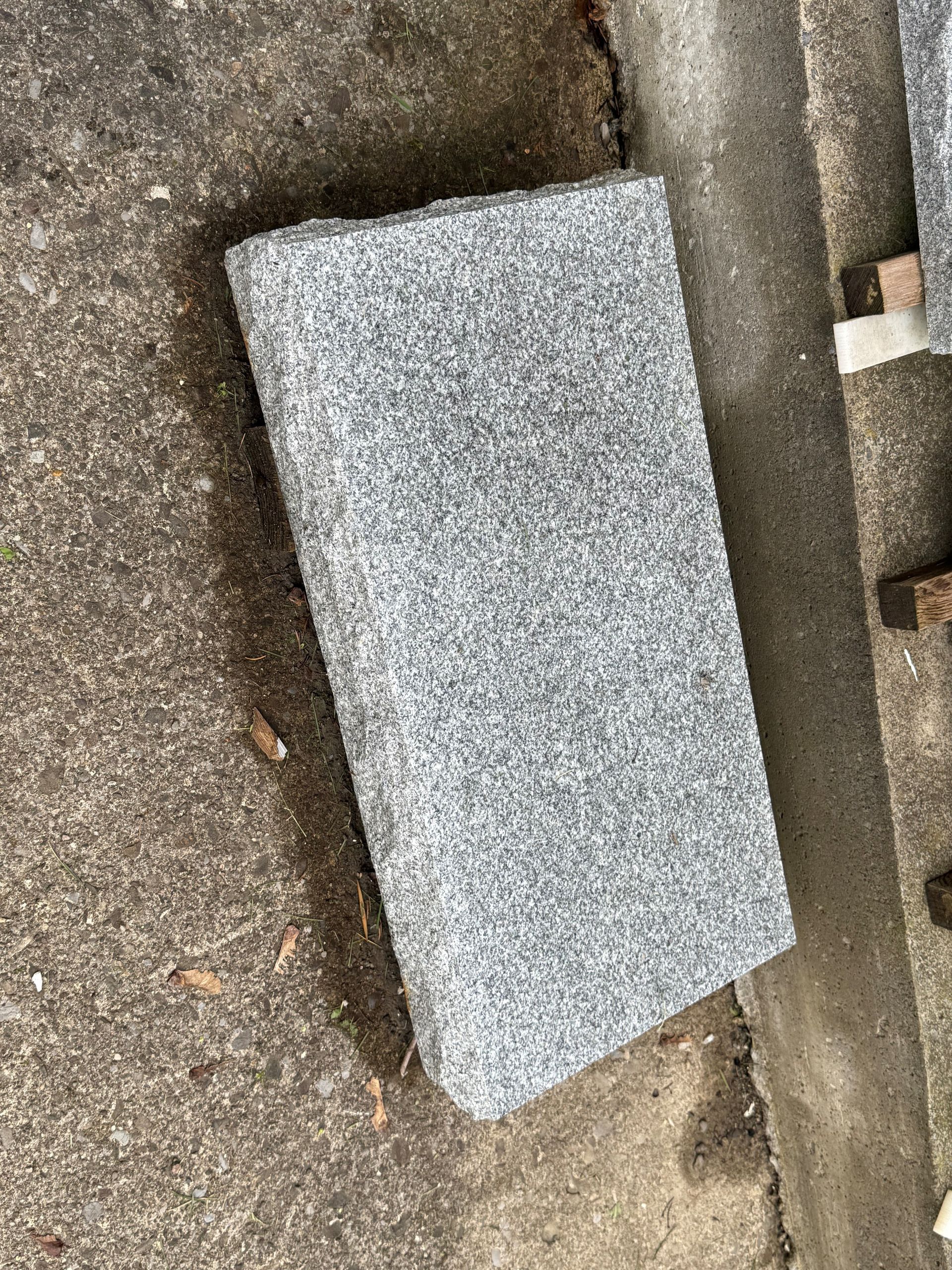 A gray granite slab is sitting on top of a concrete surface.