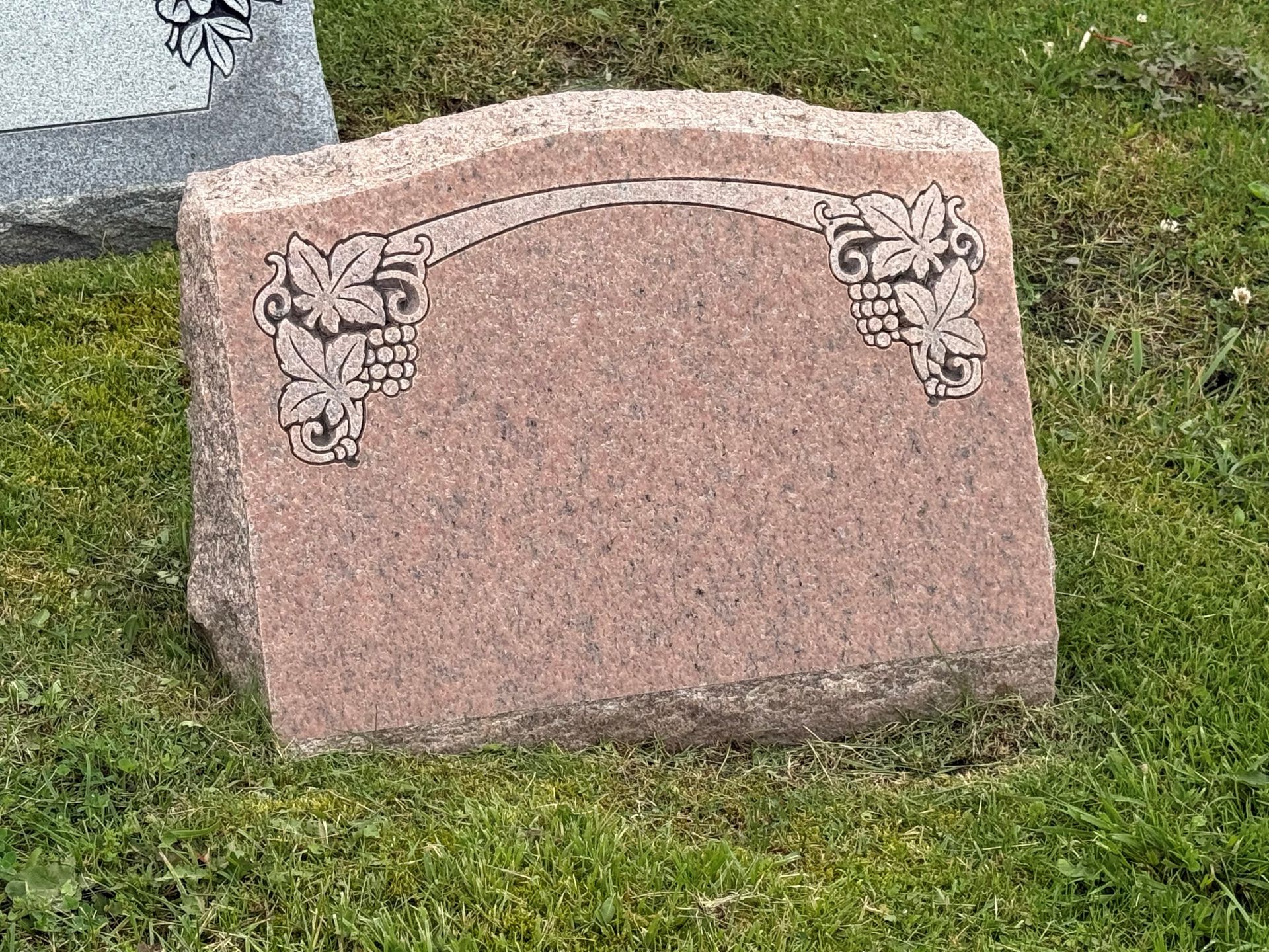 A gravestone is sitting in the grass in a cemetery.