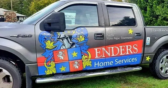 Grey pickup truck with colorful “Zenders Home Services” branding and star decals parked outdoors