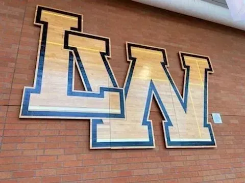 Blue-and-gold LN letters mounted on a brick wall