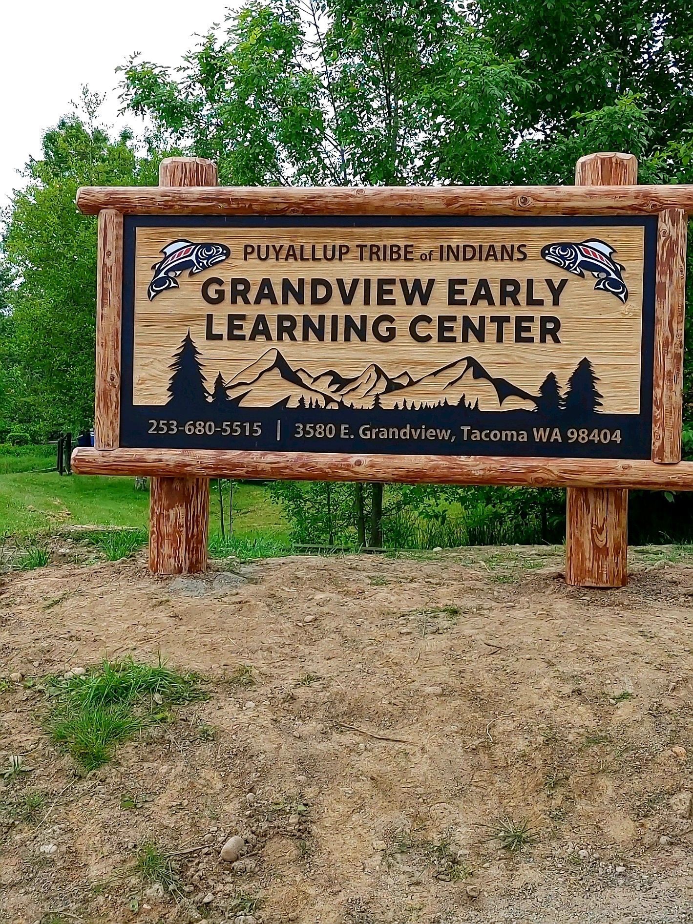 Wooden sign for Grandview Early Learning Center in front of trees and grass