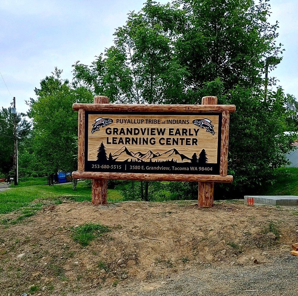 Wooden sign for Grandview Early Learning Center beside a grassy roadside with trees in the background