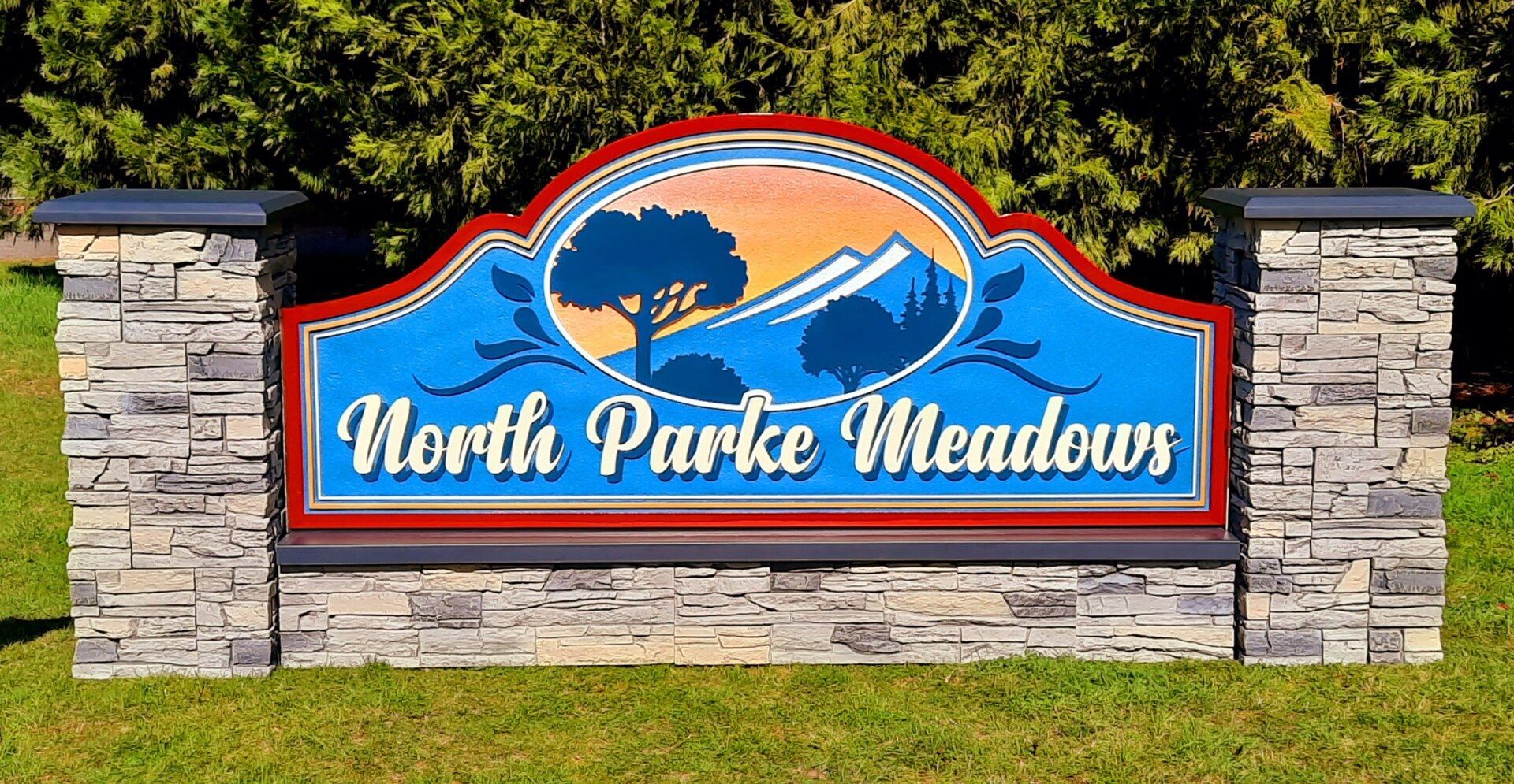 North Park Meadows neighborhood entrance sign with blue and orange design on stone pillars