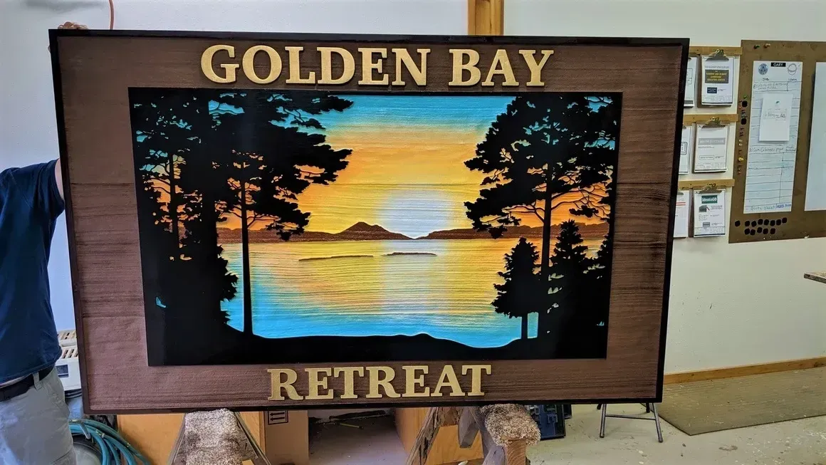 Golden Bay Retreat sign with sunset beach scene framed in dark wood