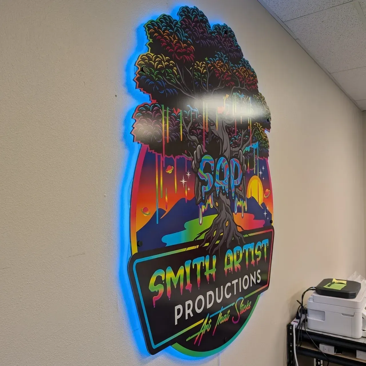 Neon-style wall sign with colorful clouds and “Smith Artists Productions” in a hallway