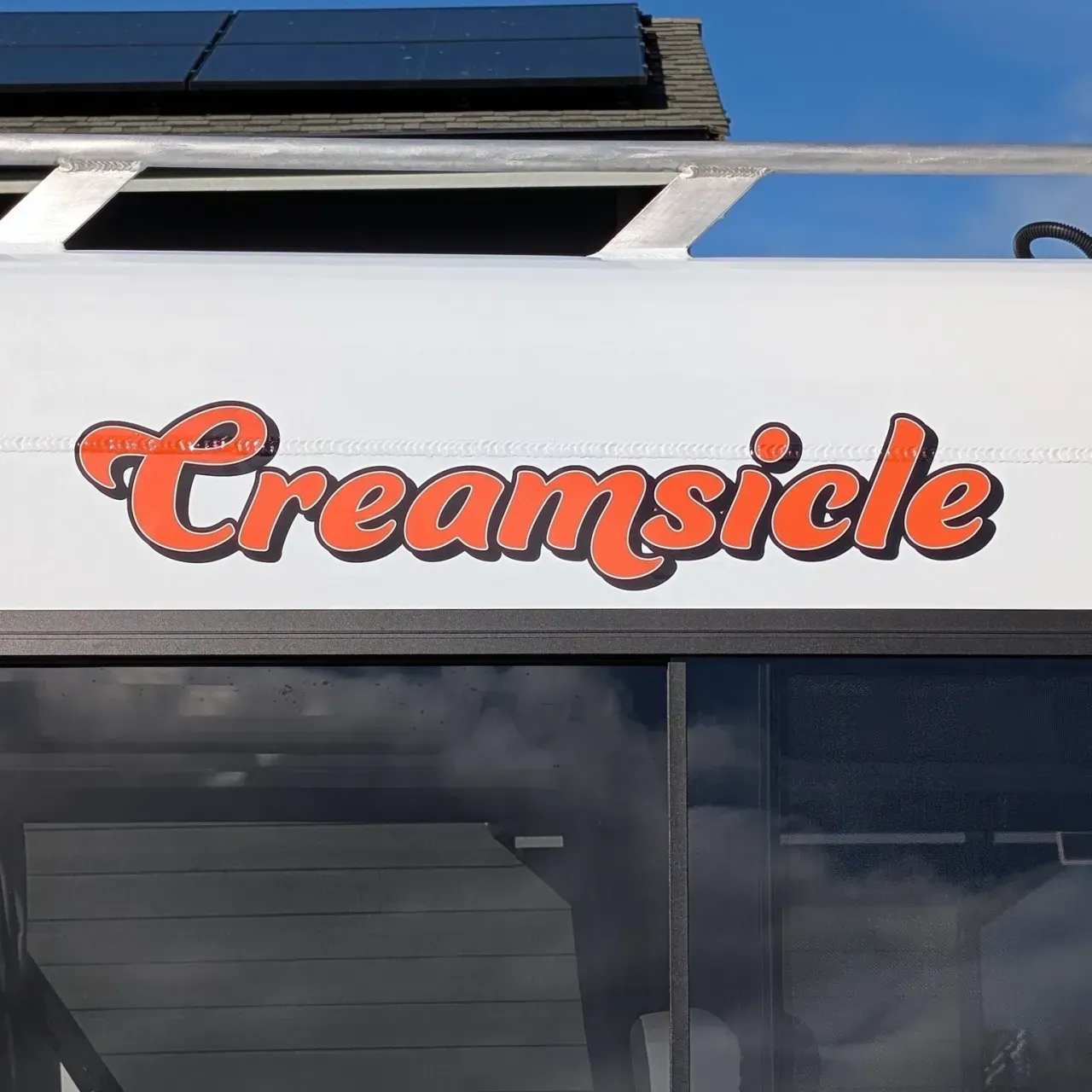 Orange “Creamsicle” sign on a storefront awning above dark windows