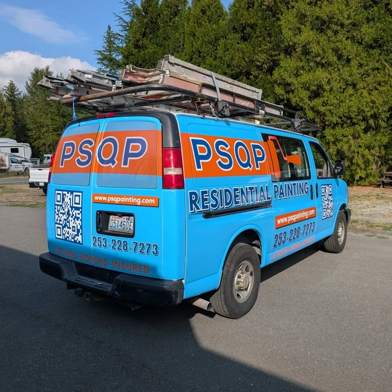 Blue PSQP plumbing van with ladder on top, parked on a street in daylight