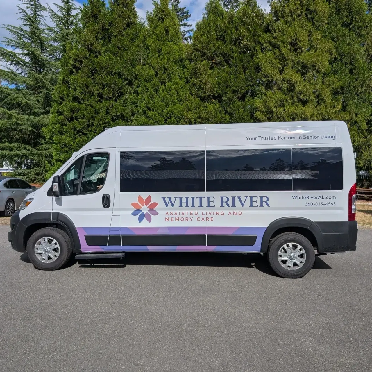 White River shuttle van parked on pavement with trees in the background