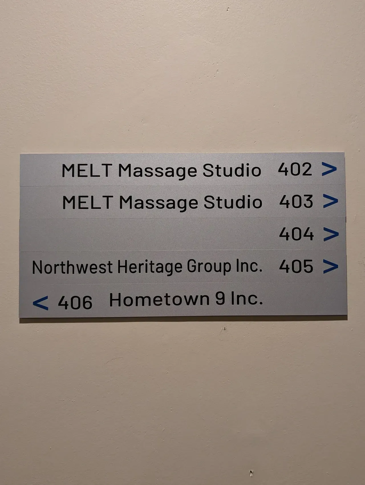 Wall directory sign listing MELT Massage Studio and Northwest Heritage Group with suite numbers 402–406.