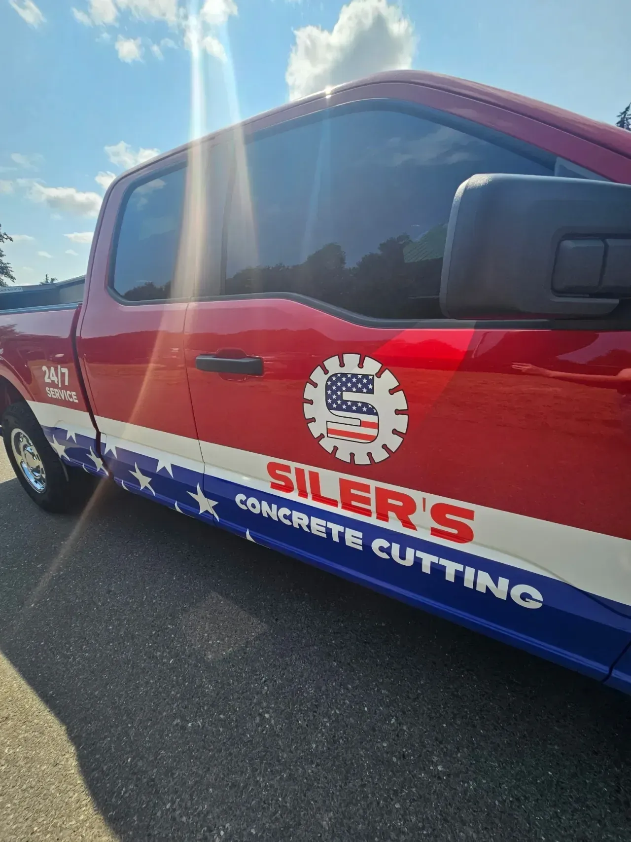 Red, white, and blue Silers Concrete Cutting pickup truck parked outside on a sunny day