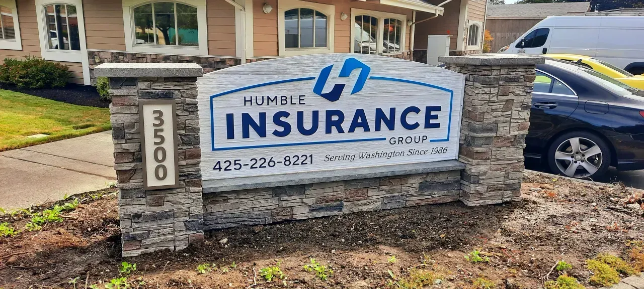 HomeLife Insurance sign on stone pillars outside an office building, with a parked car nearby.