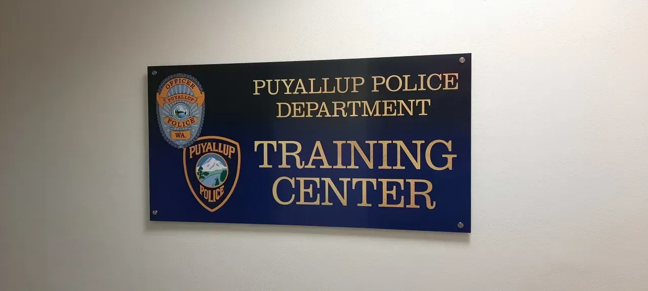 Blue wall sign for Puyallup Police Department Training Center with department badges