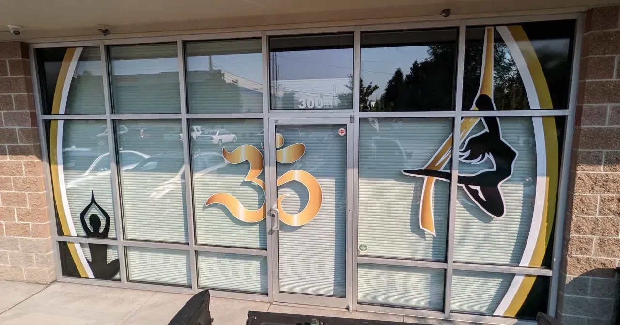 Storefront window with orange Om symbol and black decorative graphics on frosted glass panels