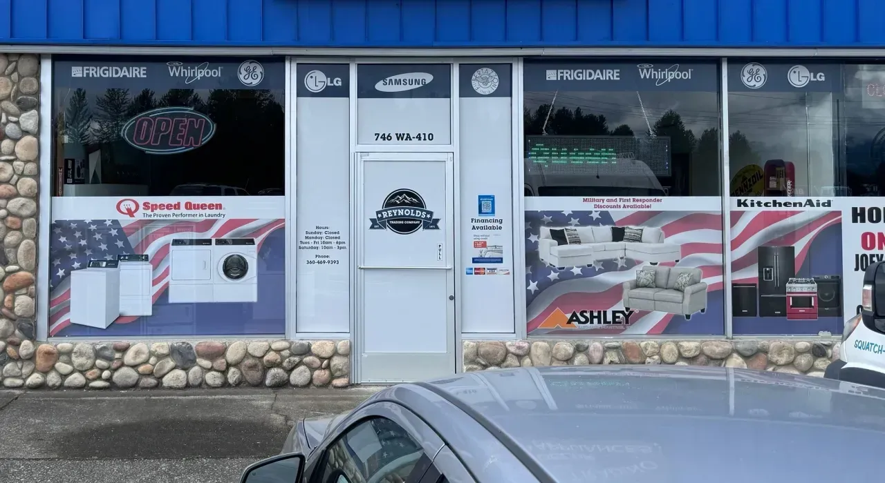 Auto repair shop storefront with posters, stone facade, and a parked car in front