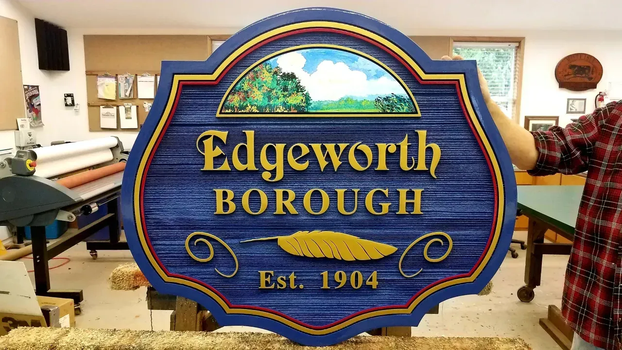 Blue-and-gold Edgeworth Borough sign with “Est. 1904” displayed indoors