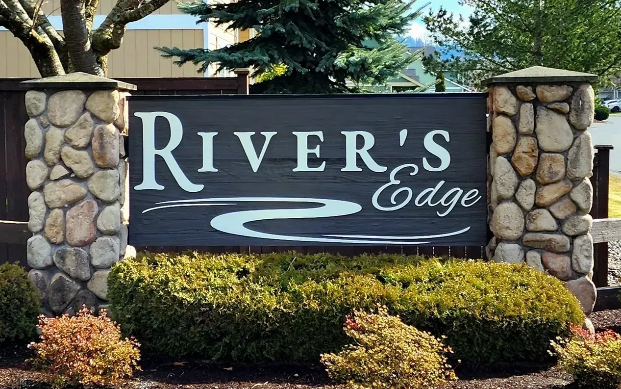 River’s Edge sign on stone pillars with shrubs in front outdoors created by Valley Sign