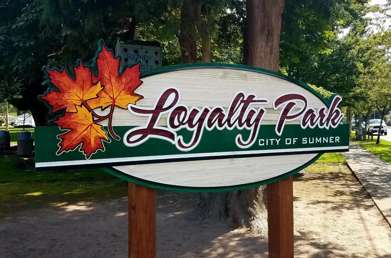 Loyalty Park sign with red maple leaves in a wooded outdoor setting, City of Sumner.