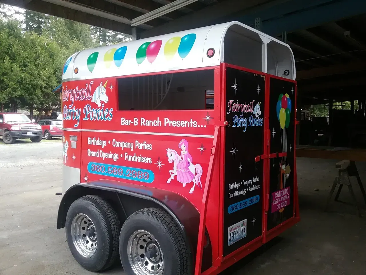 Red concession trailer with colorful graphics parked under a covered area.