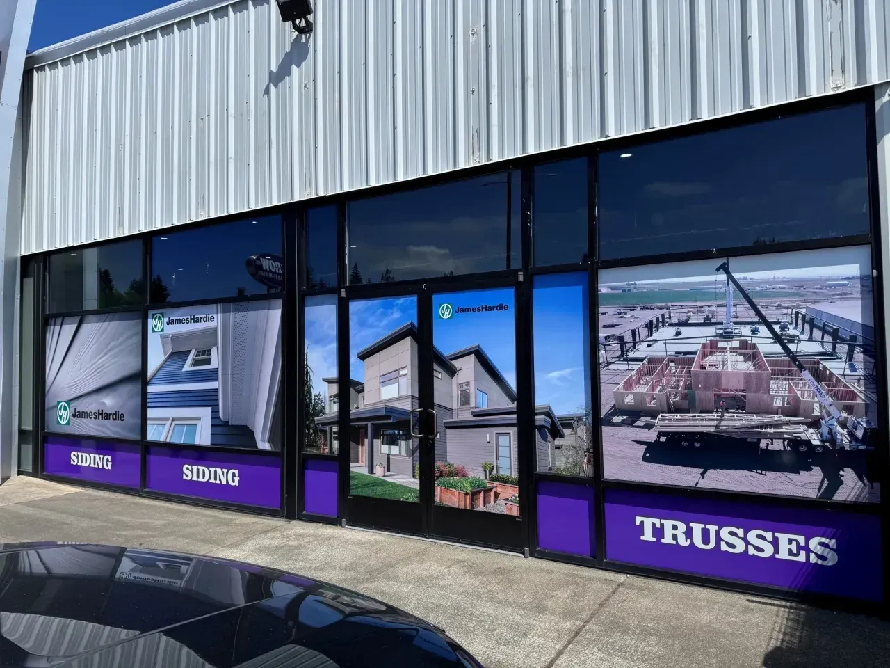 Storefront with purple TRUSSES signs and large window graphics on an industrial building.
