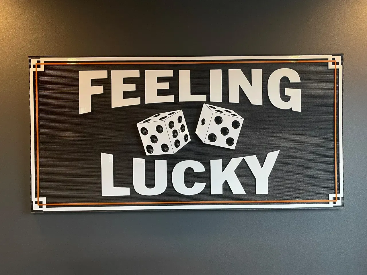 Black sign reading “FEELING LUCKY” with two dice on a wall