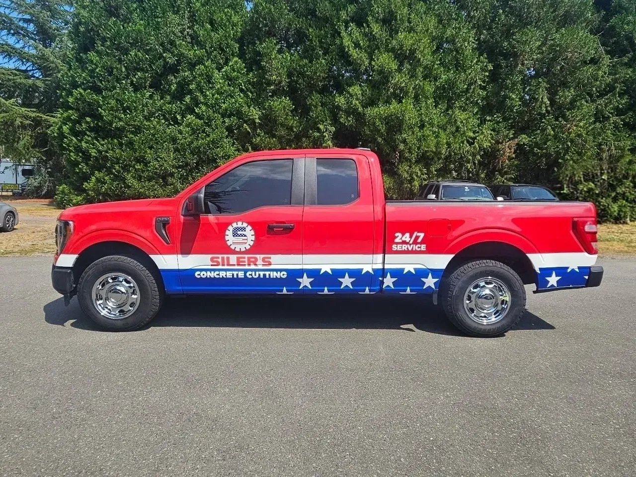Red sheriff pickup truck with patriotic stars and stripes decals parked on pavement.