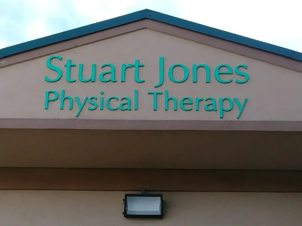 Stuart Jones Physical Therapy sign on a tan building with a teal roof trim