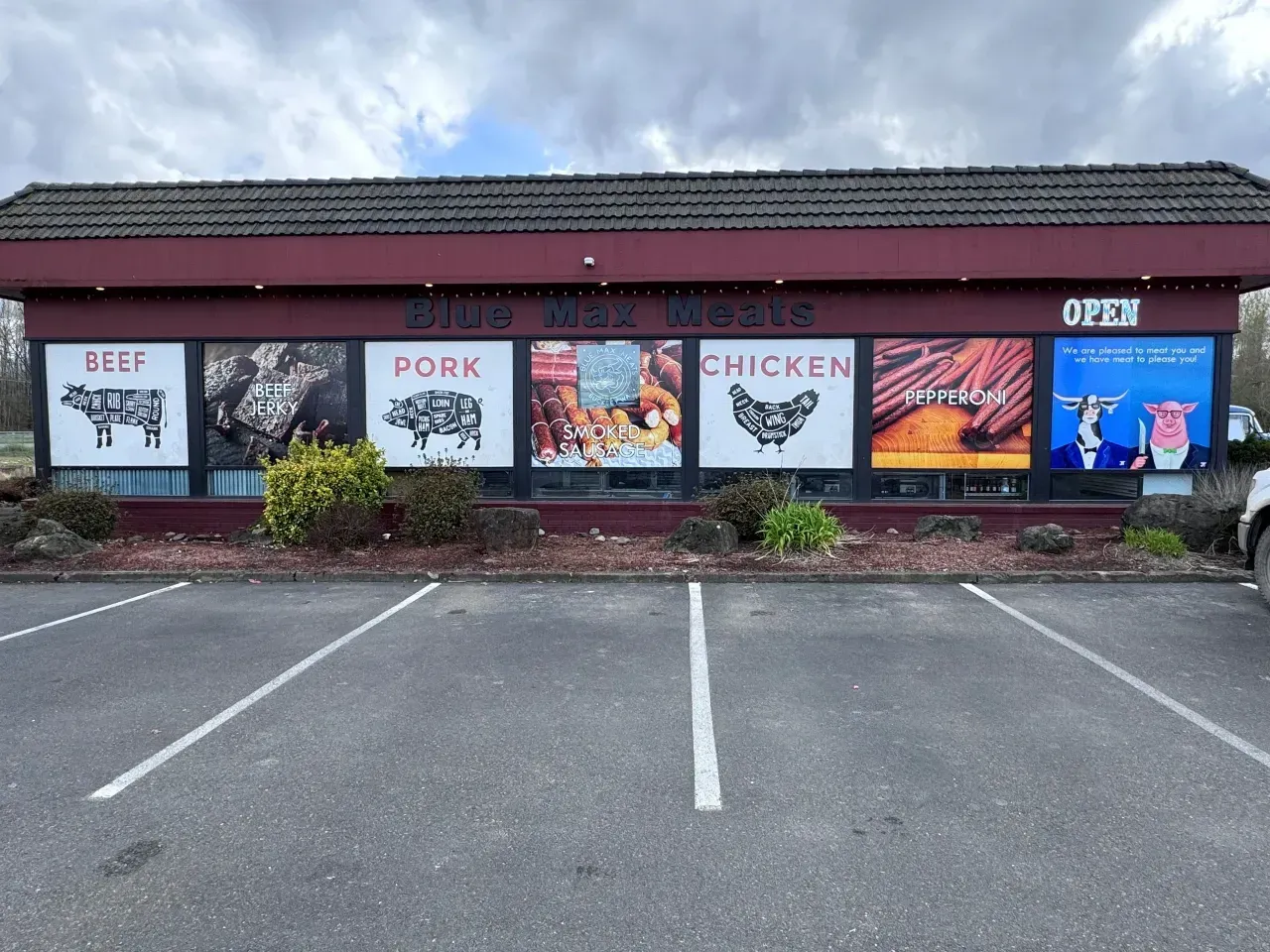 Restaurant storefront with beef, pork, chicken, and seafood menu signs above empty parking spaces