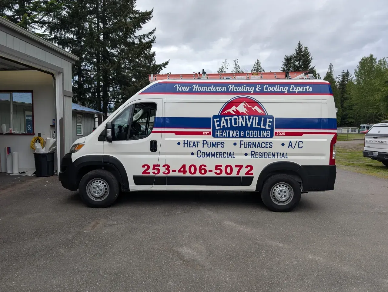 White EATWELL Food Truck parked outside a building, with red and blue lettering and phone number 253-406-5072