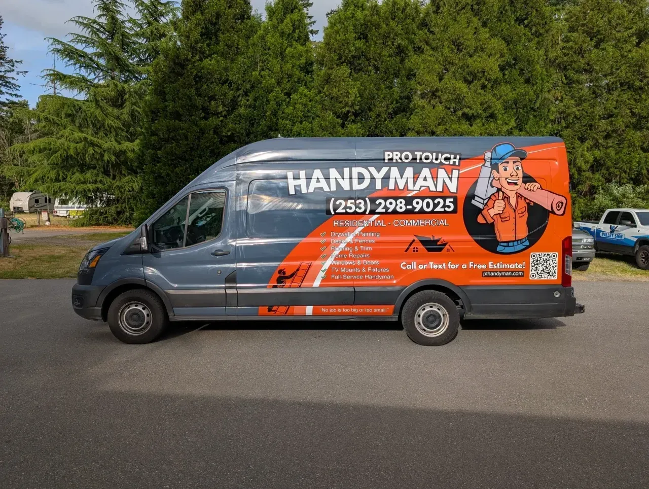 Handyman service van parked on a street, with orange and gray branding and a cartoon worker on the side