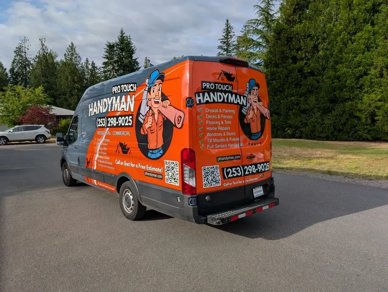 Orange and blue handyman van parked on a road beside trees