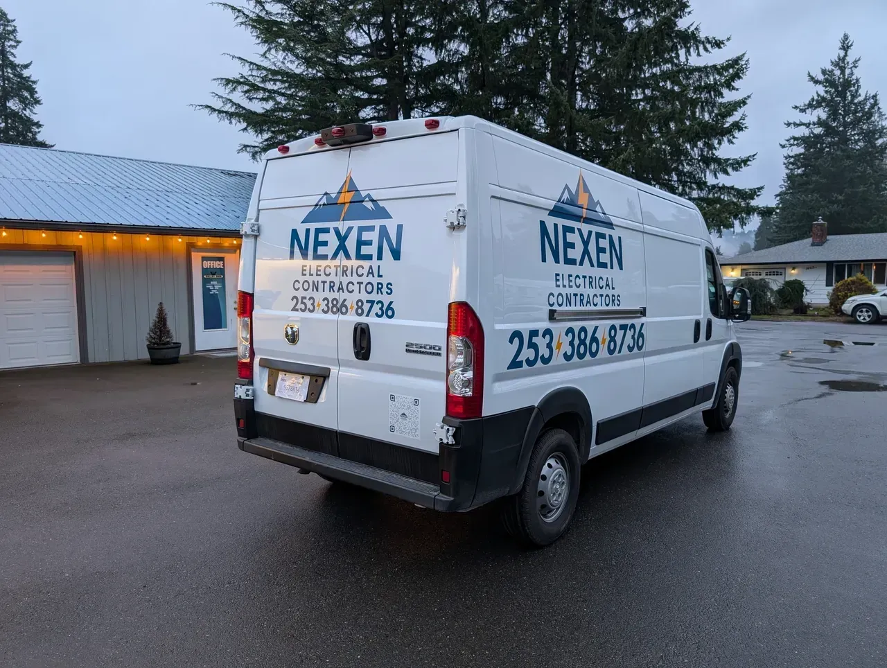 White Nexen service van parked outside a building on a rainy day
