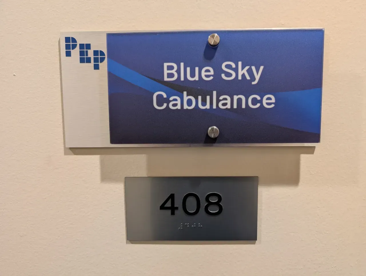 Blue Sky Cabulance sign above room 408 on a wall, blue and white with a gray number plaque