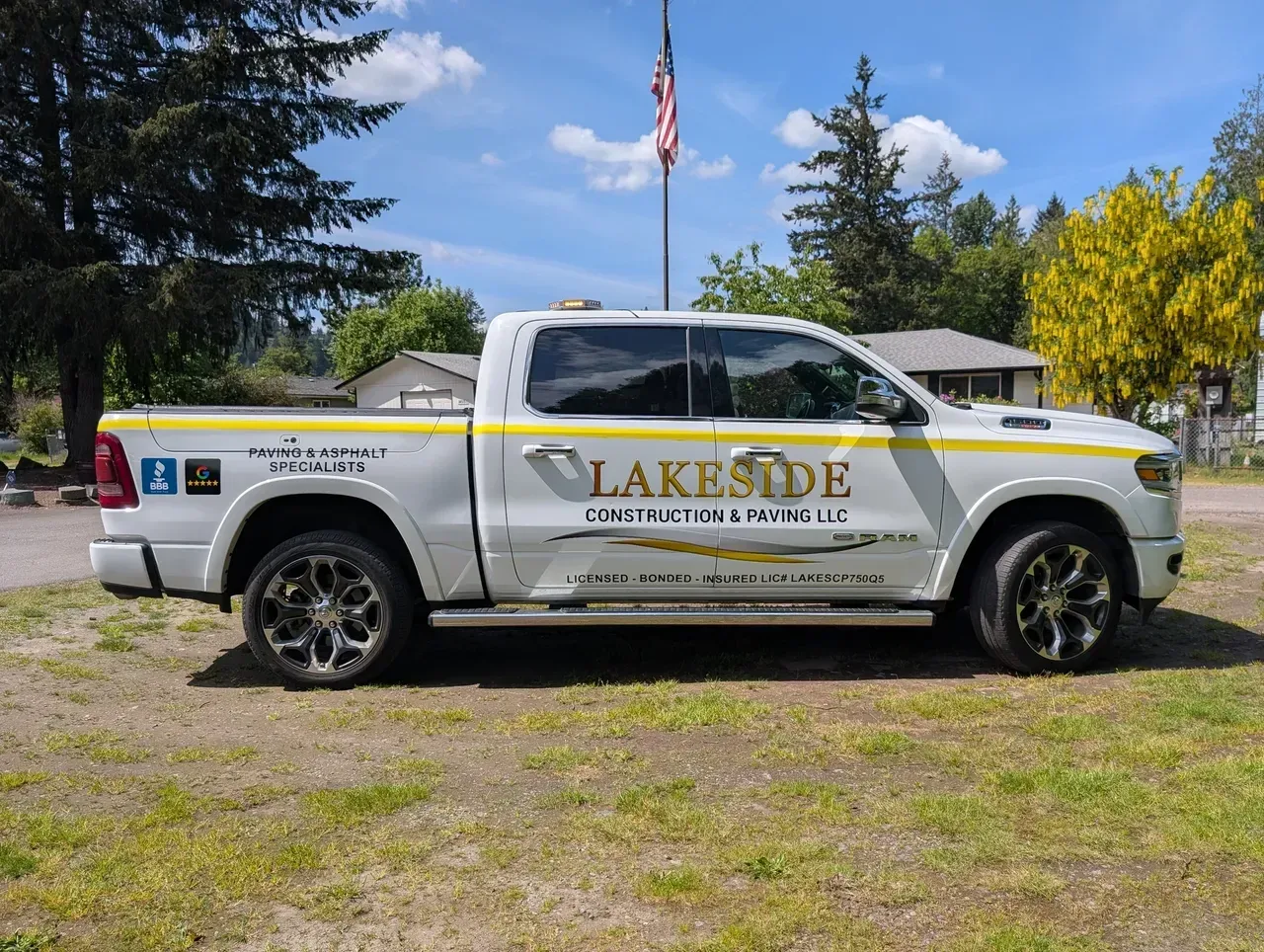 White Lakeside Service pickup truck parked on gravel with trees and a flagpole behind it.