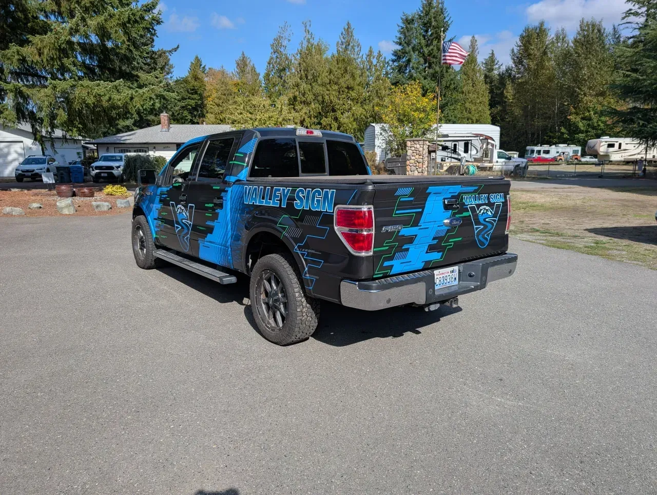 Black pickup truck with blue graphics parked on a road in a wooded campground
