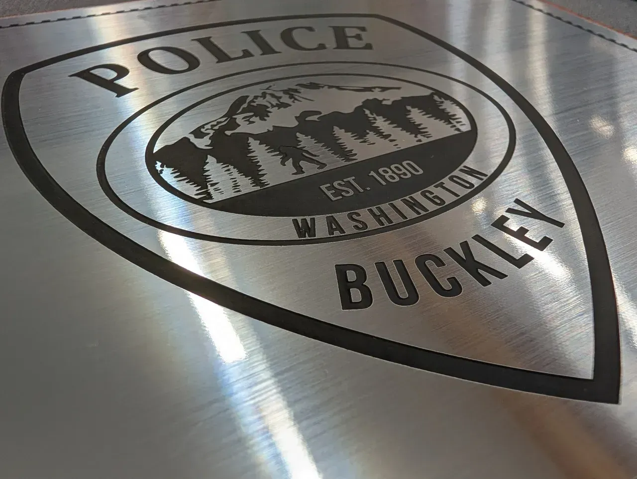 Buckley Police shield logo on a vehicle, black and white with mountain scene.