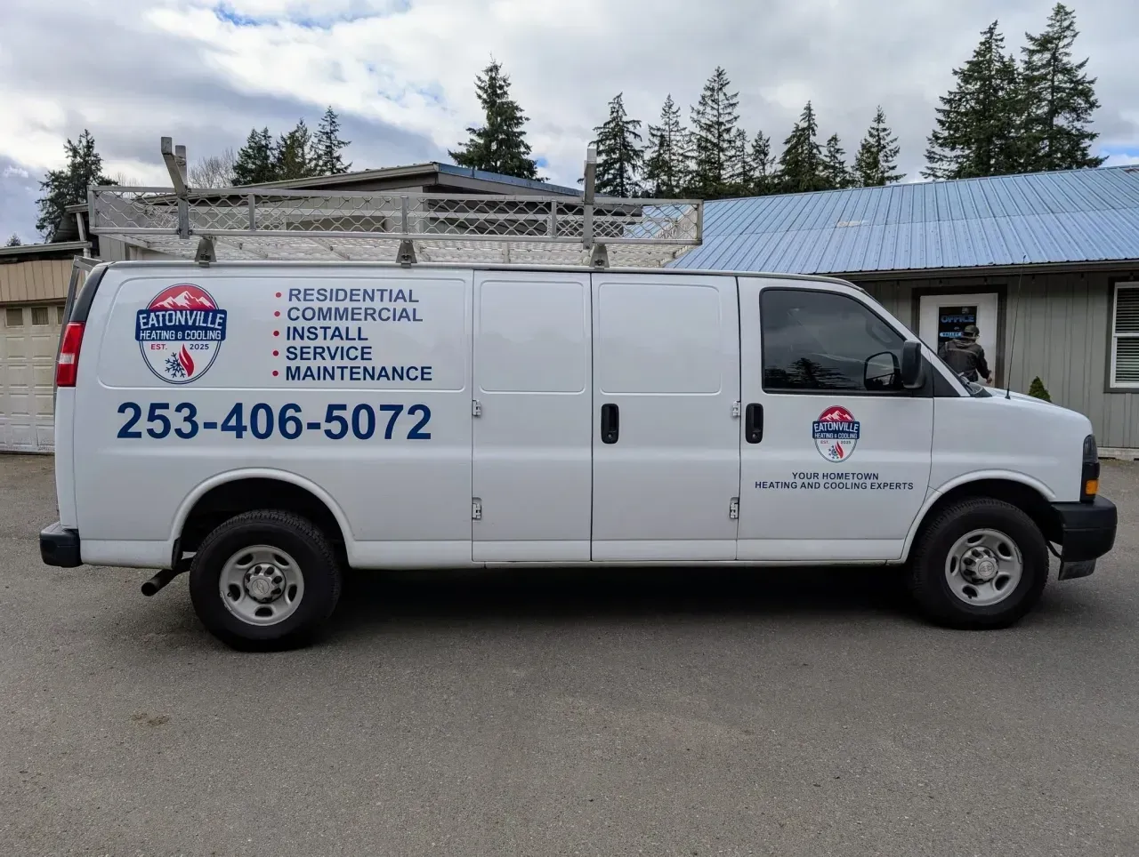 White plumbing service van with blue logo and phone number parked outside a building