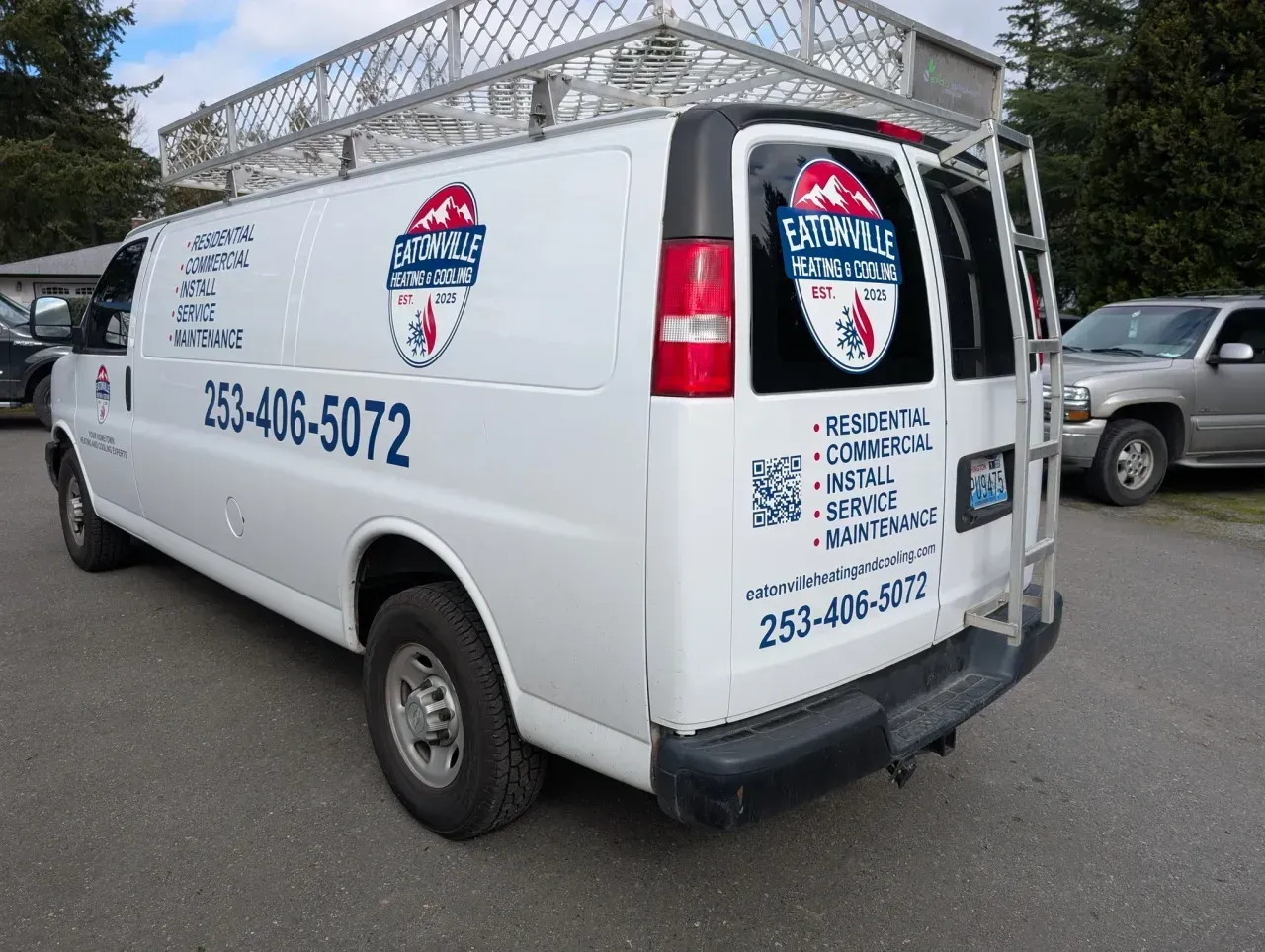 White service van with business logo and phone number parked outdoors near a building