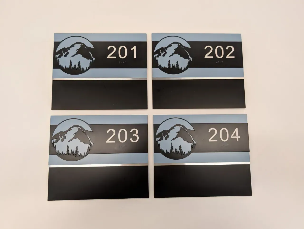 Four black-and-silver room plaques labeled 201, 202, 203, and 204 in a 2x2 grid.