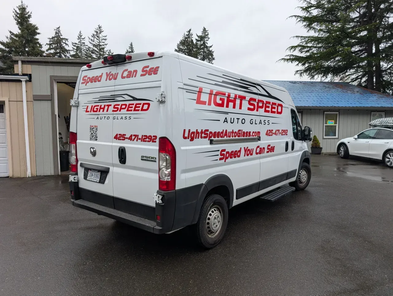 White Light Speed service van parked on a wet lot beside buildings, with red branding visible on the side.
