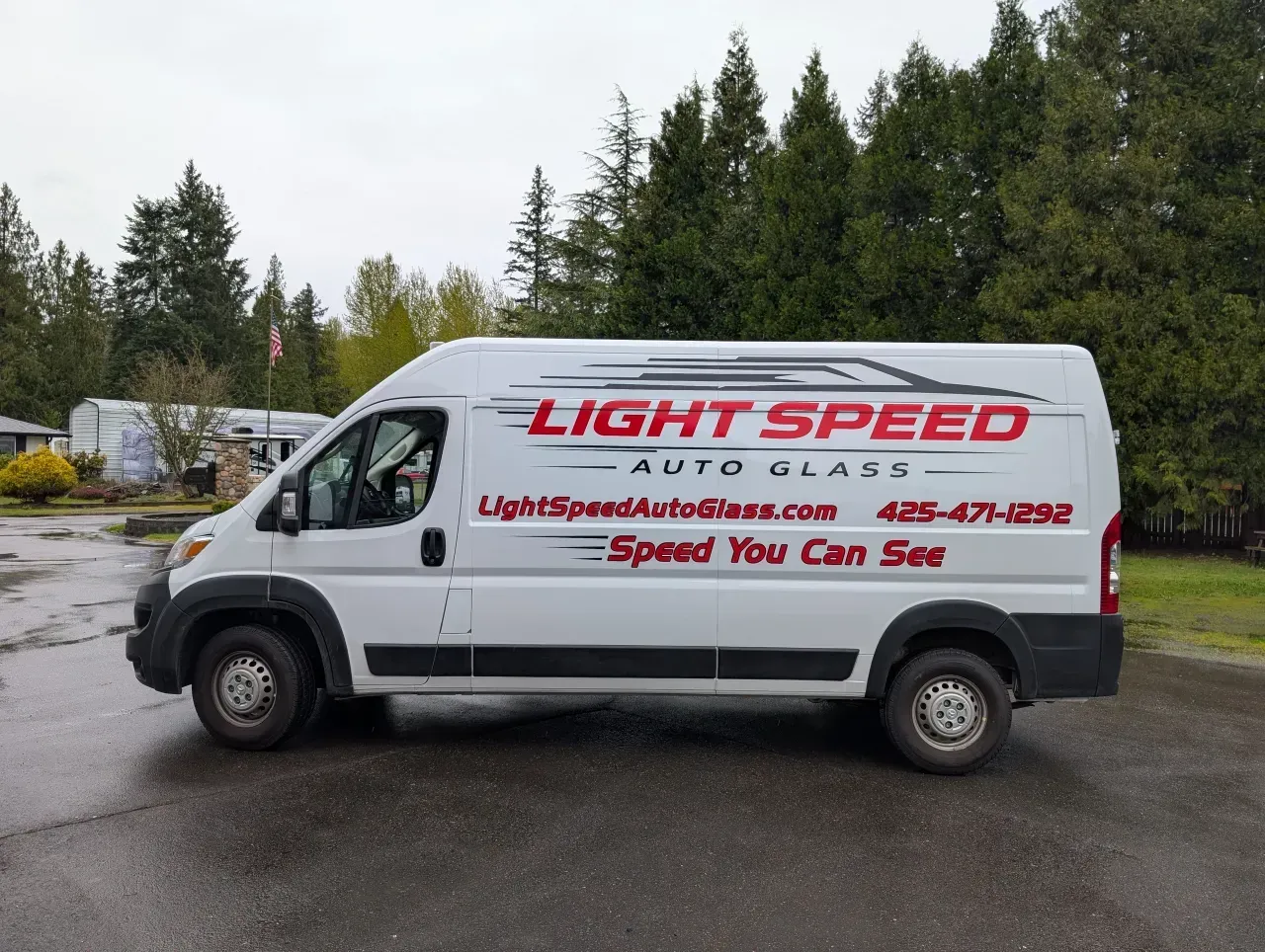 White Lightspeed Auto Glass van parked outdoors with trees in the background